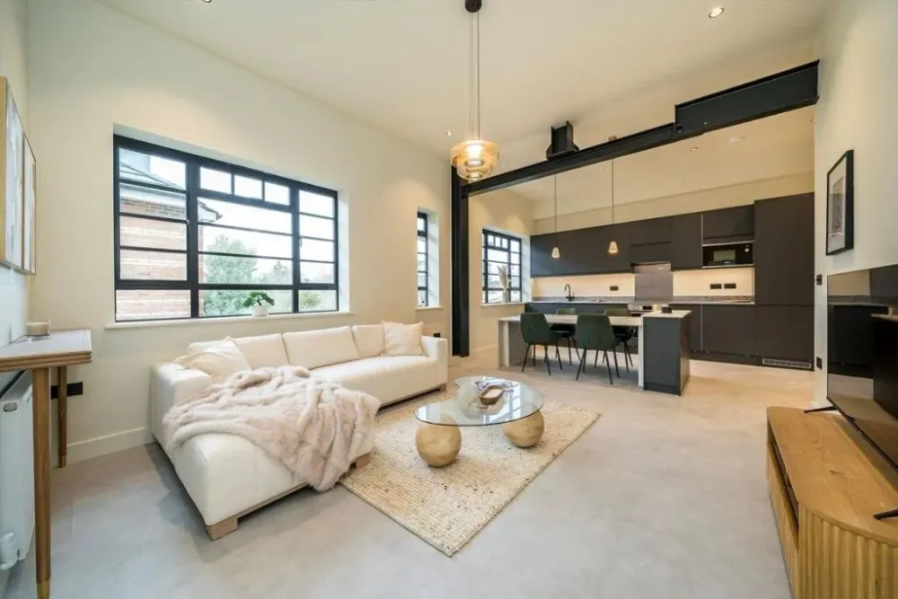 Open-plan apartment with a cream sofa, glass coffee table and dark kitchen