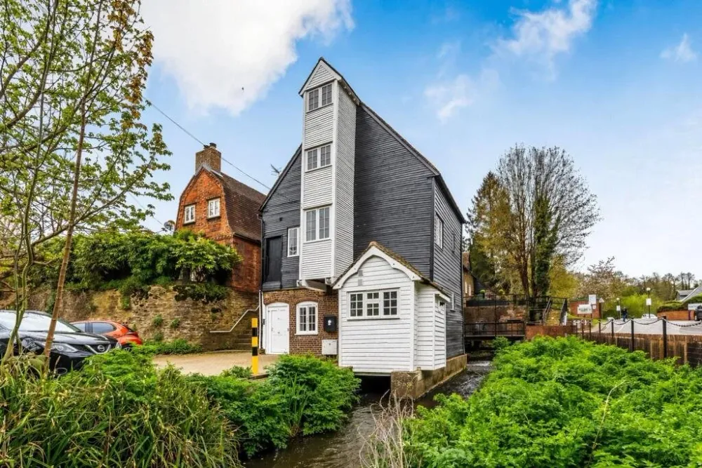 The black and white weatherboarded mill building beside the stream
