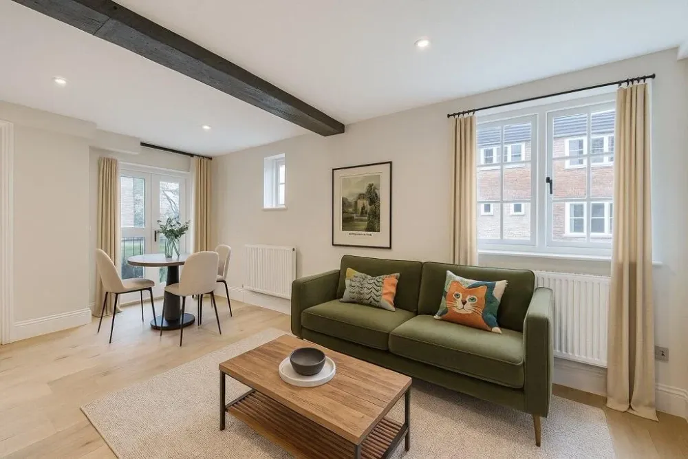 Living room with a green sofa and a dining table by the windows