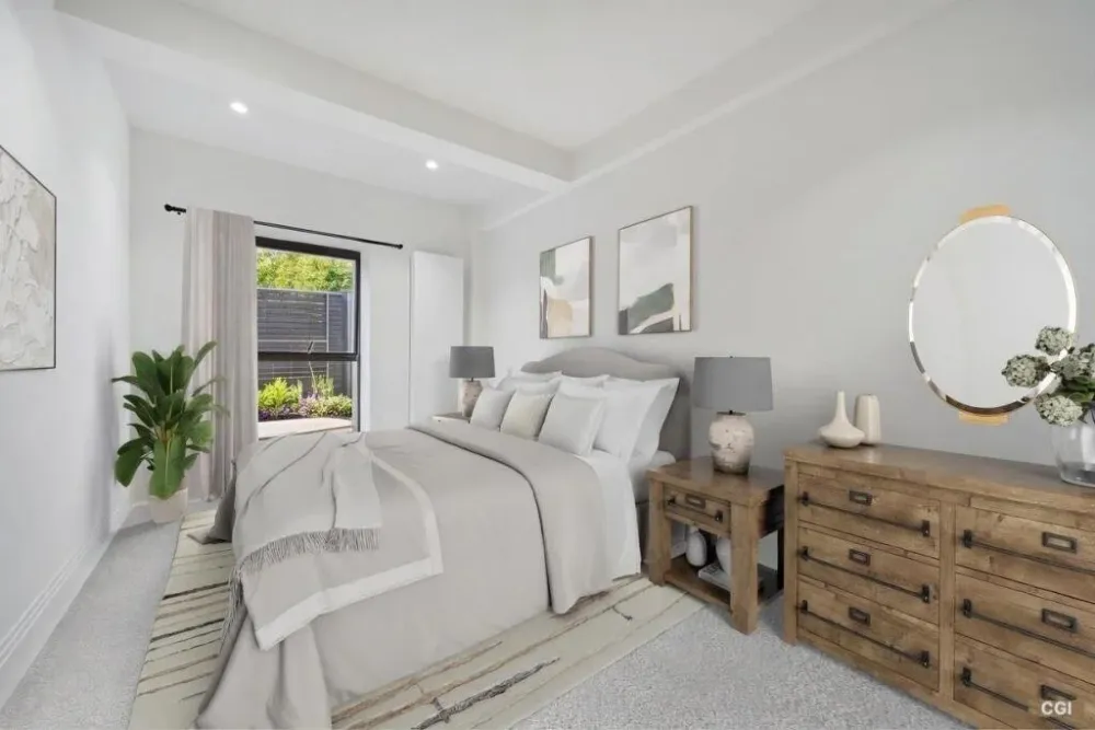 Bedroom with a large bed, wooden dresser and round mirror