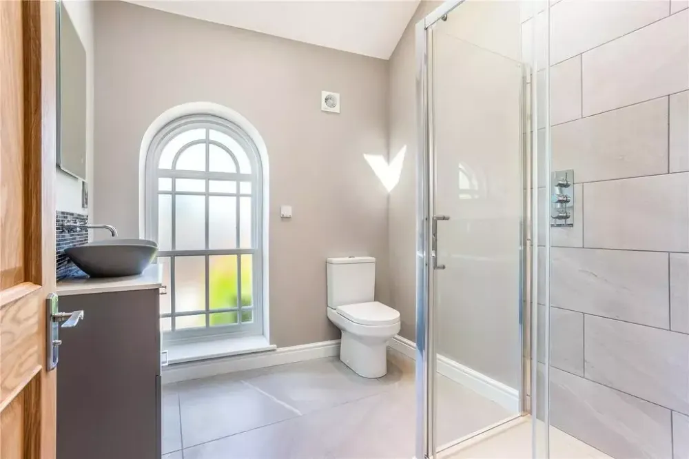 Bathroom with a large arched window and a walk-in shower