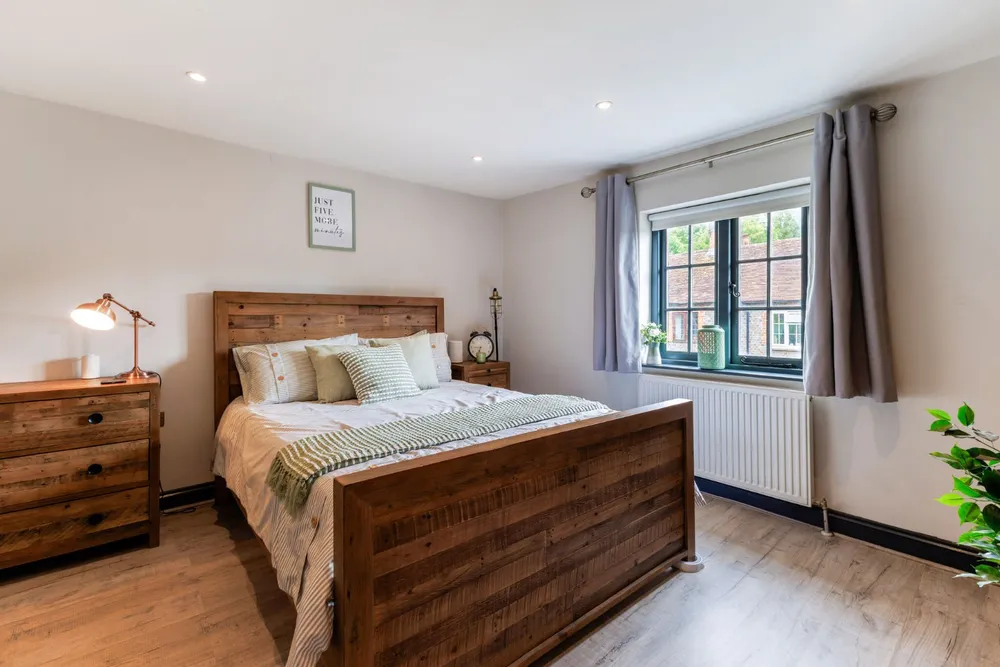 Bedroom with a timber bed, oak floors and cottage windows
