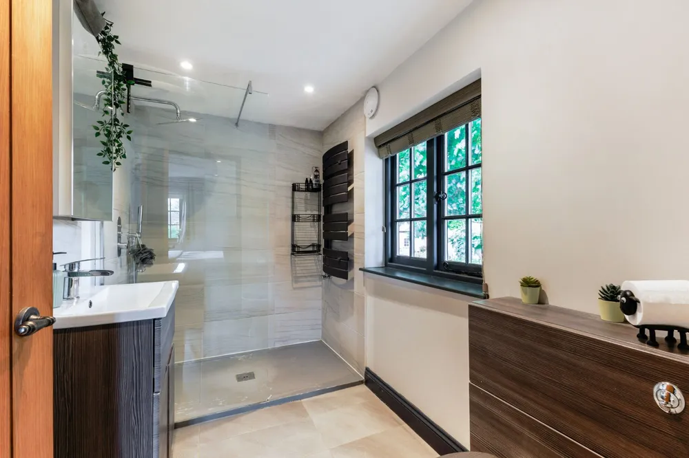 Shower room with a walk-in shower, pale stone tiles and a dark timber vanity