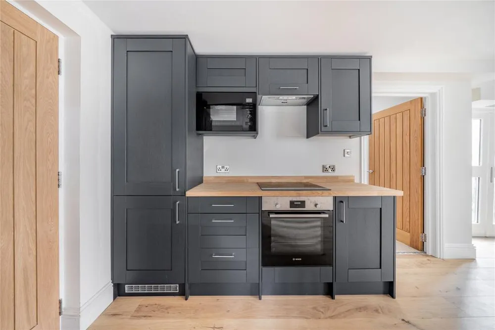 A compact dark grey kitchen with built-in oven and microwave