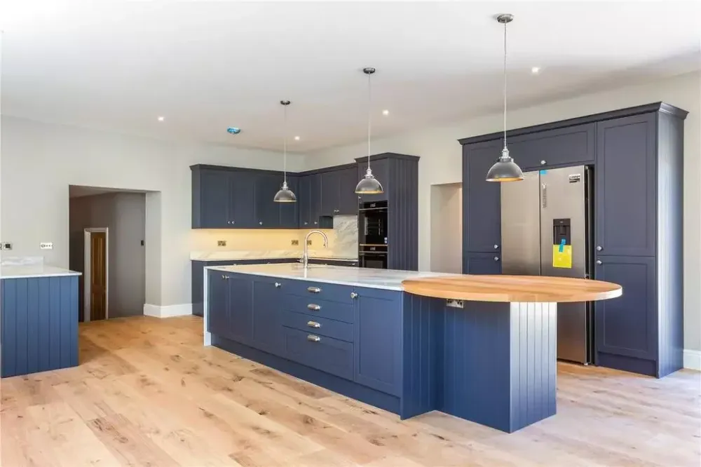 Kitchen with blue units, a wooden-topped island and pendant lights
