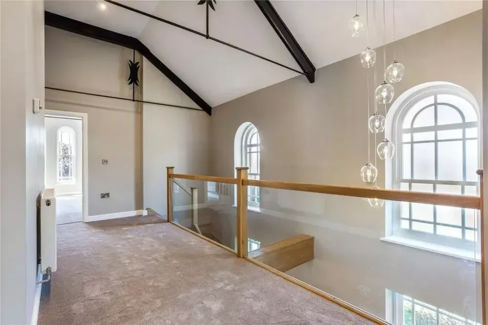 Landing on the new upper floor, with a glass balustrade and the chapel’s arched windows