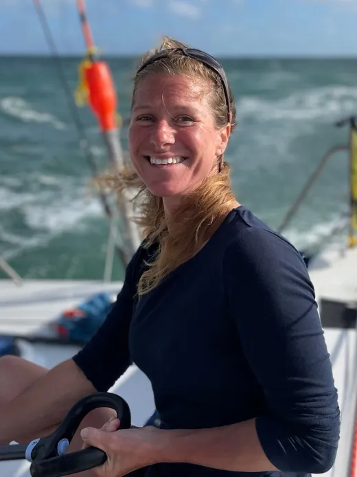 Marcella Bingley, founder and Principal Designer of River Bee Design, smiling at the helm of a sailing boat at sea